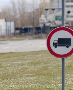 Close-up photo of the No trucks permitted road sign with a parking in the background