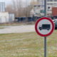 Close-up photo of the No trucks permitted road sign with a parking in the background