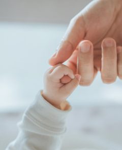 Close-up little hand of child baby holding hand of mother, A newborn holds on to mom's, dad's finger, Love and relationship with infant, Care and support, Dreaming and protection