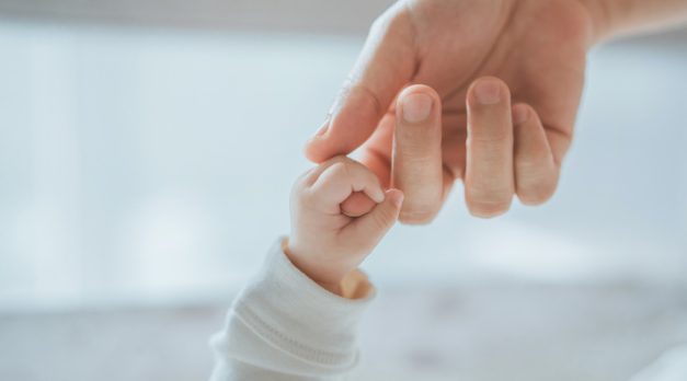 Close-up little hand of child baby holding hand of mother, A newborn holds on to mom's, dad's finger, Love and relationship with infant, Care and support, Dreaming and protection